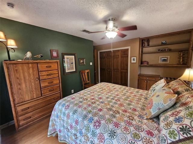 bedroom with a textured ceiling, light hardwood / wood-style floors, a closet, and ceiling fan