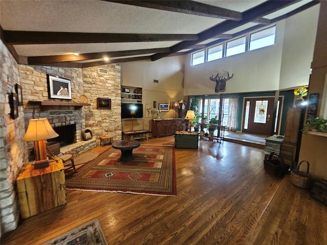 living room with beamed ceiling, a stone fireplace, a textured ceiling, and high vaulted ceiling