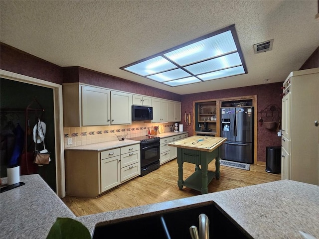 kitchen featuring black appliances, decorative backsplash, light hardwood / wood-style floors, and a textured ceiling