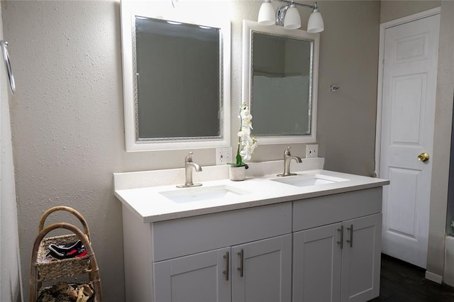 bathroom with dual sinks, wood-type flooring, and vanity with extensive cabinet space