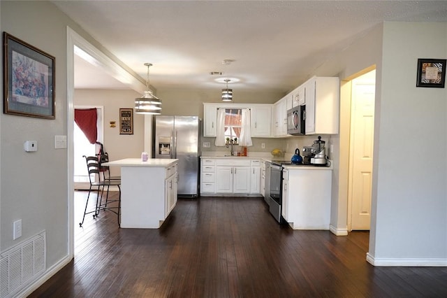 kitchen with a kitchen bar, white cabinetry, decorative light fixtures, dark hardwood / wood-style flooring, and stainless steel appliances