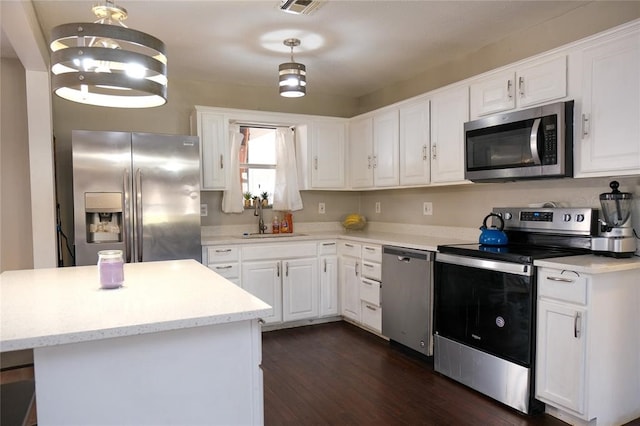 kitchen featuring decorative light fixtures, white cabinets, dark wood-type flooring, stainless steel appliances, and sink
