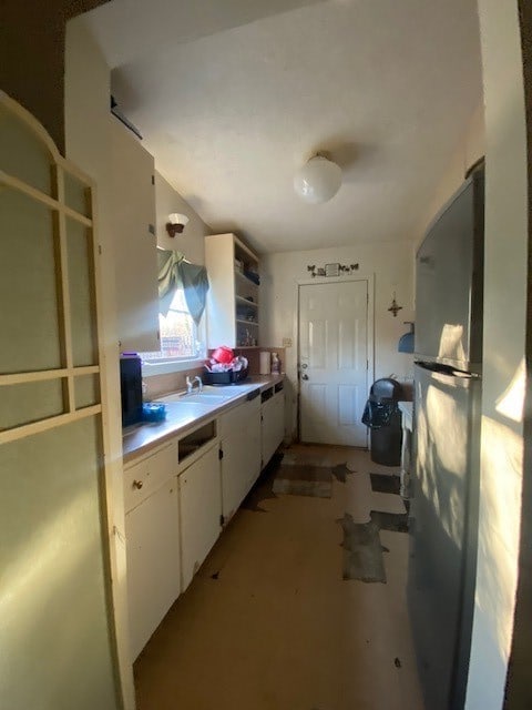 kitchen with sink, white cabinetry, and fridge