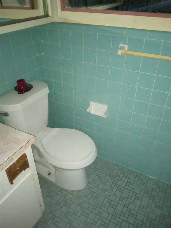 bathroom with tile walls, tile floors, vanity, and toilet