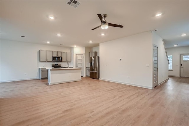 kitchen with light hardwood / wood-style floors, stainless steel appliances, a center island with sink, and gray cabinetry