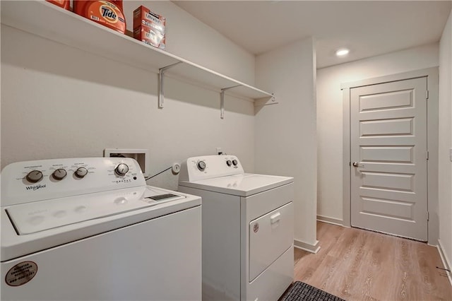 clothes washing area with separate washer and dryer and light wood-type flooring