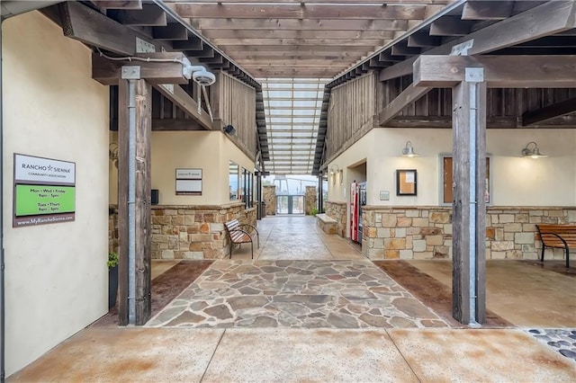 corridor with a towering ceiling, wooden ceiling, and concrete flooring