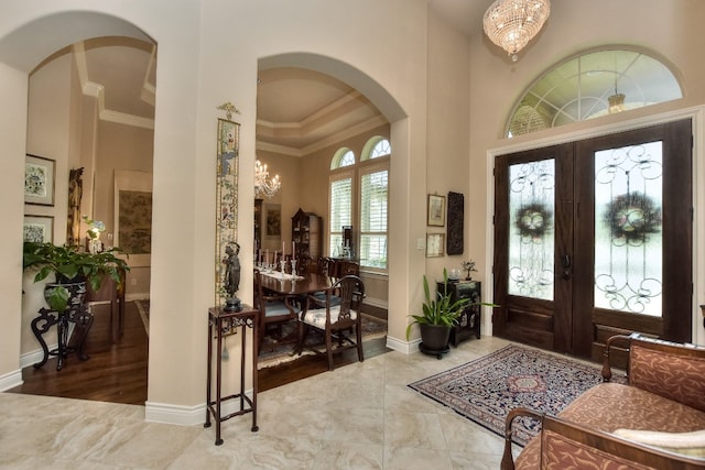 foyer entrance with french doors, an inviting chandelier, tile floors, and ornamental molding