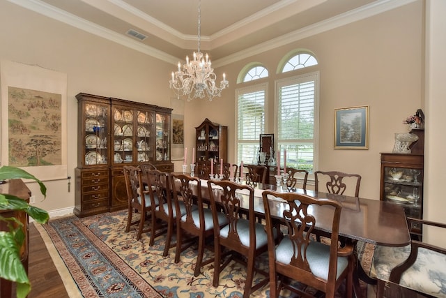 dining area with crown molding, a chandelier, hardwood / wood-style flooring, and a tray ceiling