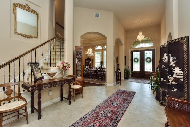 tiled foyer entrance featuring french doors, a towering ceiling, and a notable chandelier