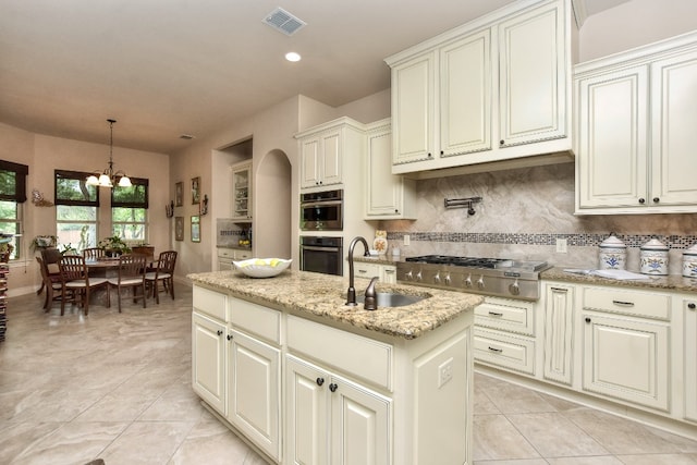 kitchen featuring hanging light fixtures, a chandelier, tasteful backsplash, sink, and light tile floors