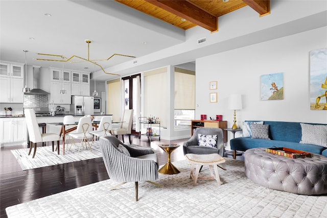 living room featuring beamed ceiling, a chandelier, and light wood-type flooring