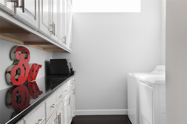 clothes washing area with washer and clothes dryer, dark hardwood / wood-style flooring, and cabinets