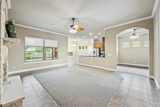 unfurnished living room with ceiling fan with notable chandelier, sink, light tile patterned floors, and ornamental molding