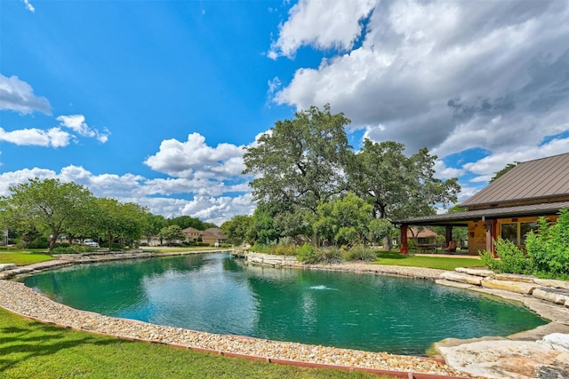 view of swimming pool with a water view and a lawn