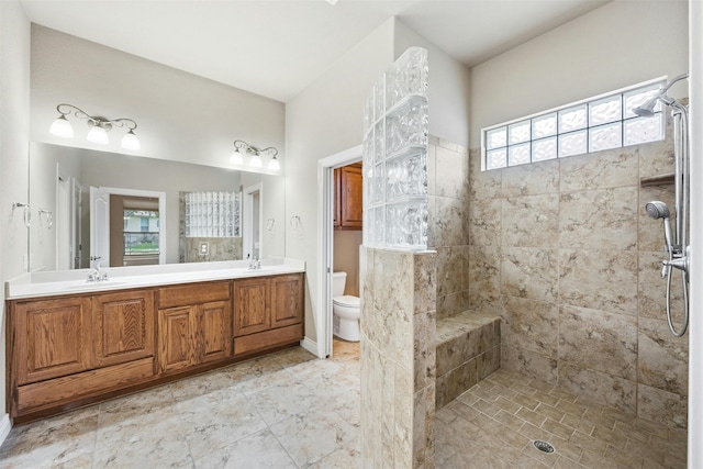 bathroom featuring vanity, toilet, and a tile shower