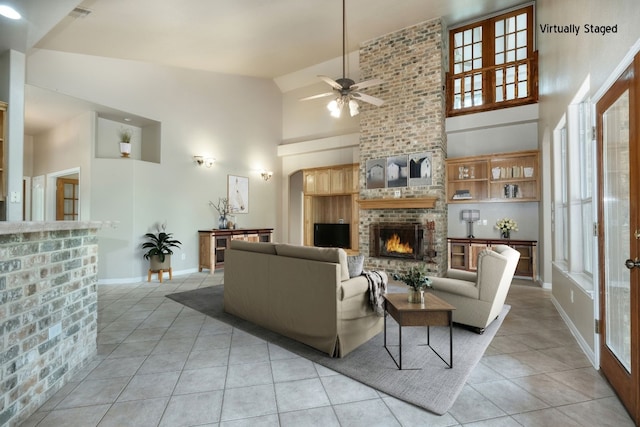 living room with high vaulted ceiling, a brick fireplace, brick wall, light tile floors, and ceiling fan