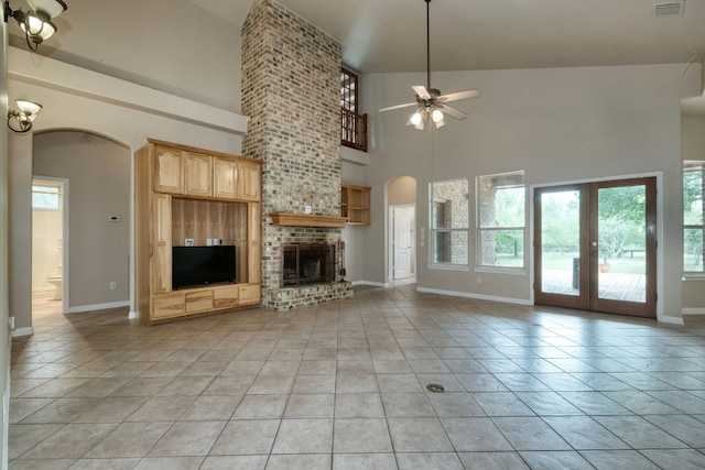 unfurnished living room with high vaulted ceiling, ceiling fan, brick wall, and a brick fireplace