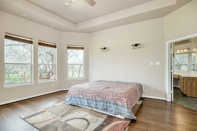 bedroom featuring ceiling fan, a tray ceiling, dark hardwood / wood-style floors, and ensuite bath