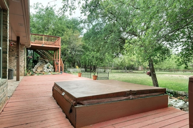 deck featuring a covered hot tub and a lawn