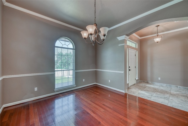 empty room featuring tile floors, a chandelier, and ornamental molding