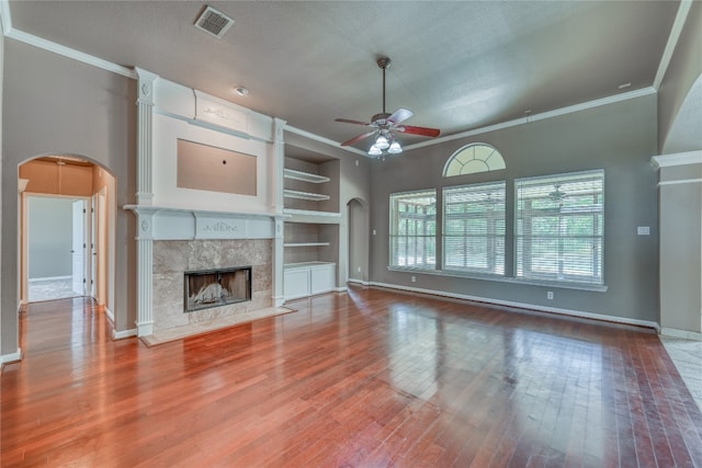 unfurnished living room featuring wood-type flooring, built in features, a high end fireplace, ceiling fan, and a textured ceiling