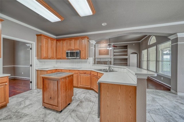 kitchen featuring ceiling fan, light tile floors, a kitchen island, sink, and tasteful backsplash