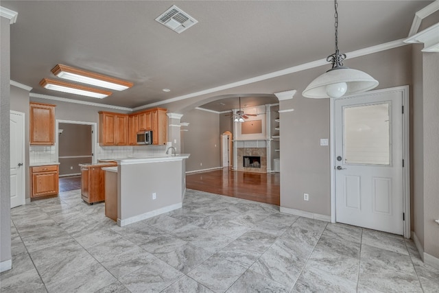 kitchen with light hardwood / wood-style floors, crown molding, ceiling fan, and a fireplace