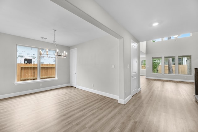 unfurnished room with a notable chandelier and light hardwood / wood-style flooring