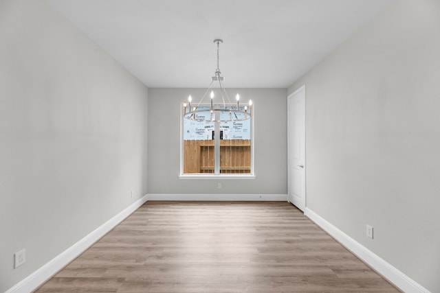 unfurnished room with a chandelier and hardwood / wood-style flooring