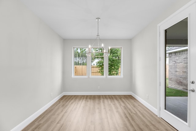 unfurnished room with a notable chandelier and light hardwood / wood-style flooring