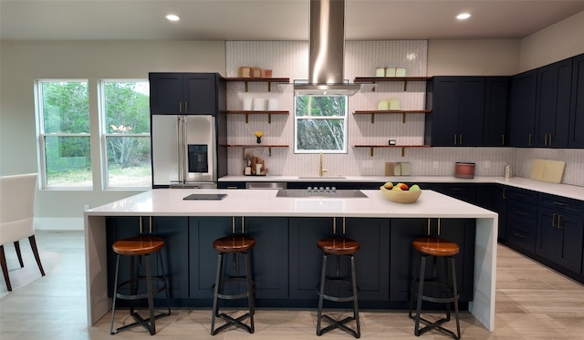 kitchen with backsplash, extractor fan, stainless steel appliances, a kitchen bar, and a kitchen island