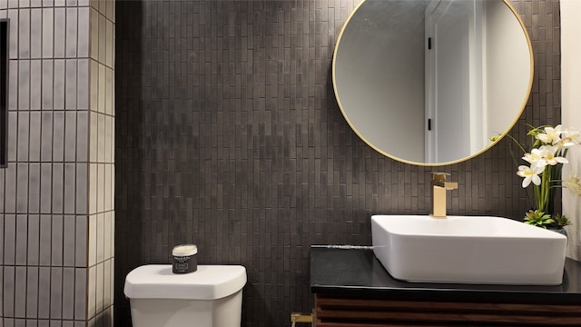 bathroom with vanity, toilet, and tile walls