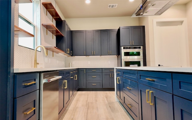 kitchen with range hood, appliances with stainless steel finishes, backsplash, and blue cabinetry