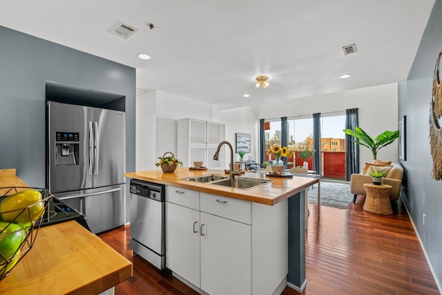 kitchen with sink, dark wood-type flooring, stainless steel appliances, and white cabinets