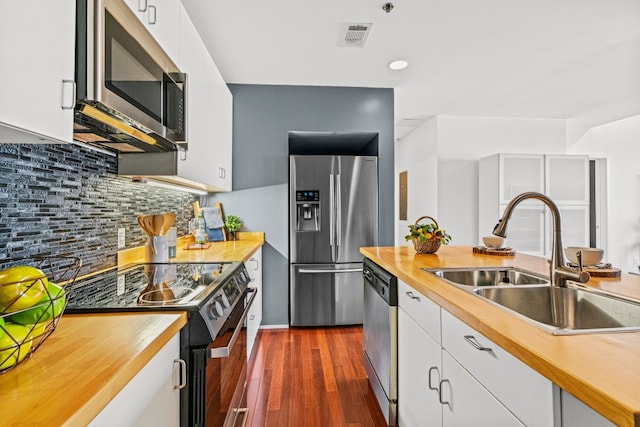 kitchen featuring dark wood-type flooring, sink, white cabinets, decorative backsplash, and stainless steel appliances