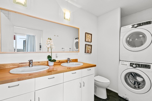 bathroom with stacked washer and clothes dryer, vanity, and toilet