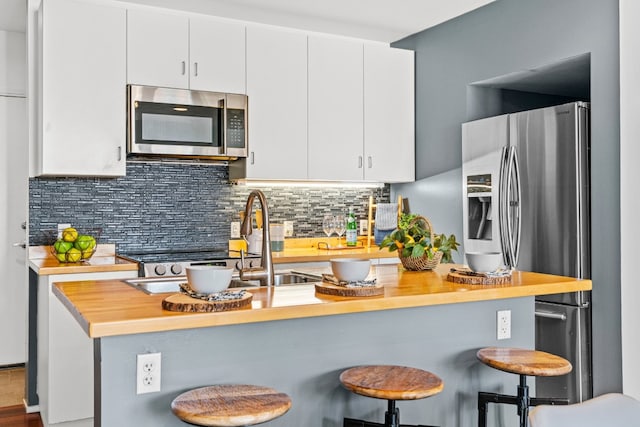 kitchen featuring tasteful backsplash, sink, white cabinetry, a kitchen breakfast bar, and appliances with stainless steel finishes