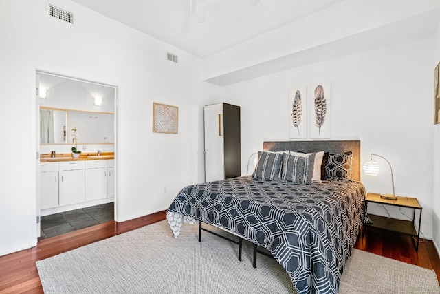 bedroom with ceiling fan, dark wood-type flooring, sink, and ensuite bath