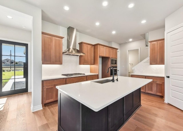 226 Flora Springs Cv, Liberty Hill, TX 78642 - kitchen featuring wall chimney exhaust hood, a sink, stainless steel appliances, light wood-style flooring, and brown cabinets
