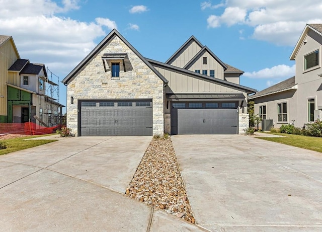 226 Flora Springs Cv, Liberty Hill, TX 78642 - view of front facade with board and batten siding, driveway, stone siding, central air condition unit, and a garage