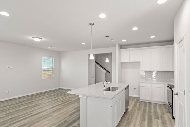 kitchen featuring white cabinetry, hanging light fixtures, sink, and a kitchen island with sink