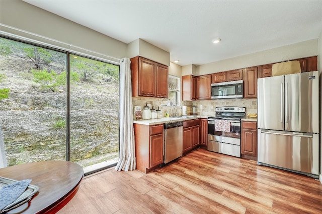 kitchen featuring plenty of natural light, stainless steel appliances, tasteful backsplash, and light wood-type flooring