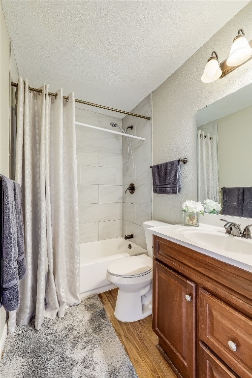 full bathroom with vanity, hardwood / wood-style floors, shower / bathtub combination with curtain, toilet, and a textured ceiling