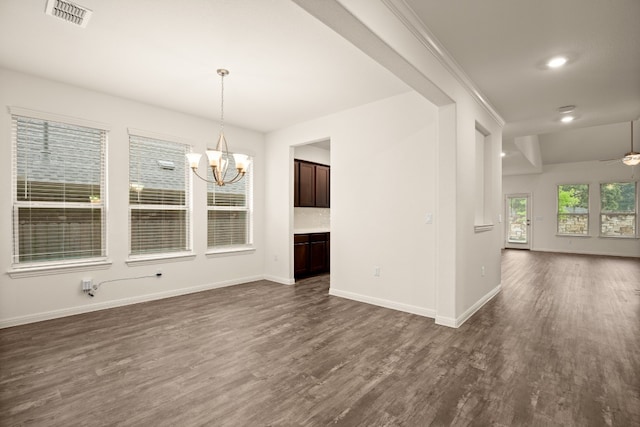 unfurnished dining area with dark wood-type flooring, ceiling fan with notable chandelier, and ornamental molding