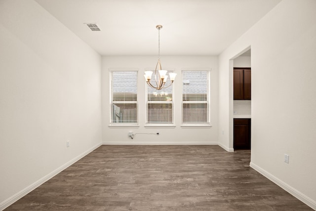 unfurnished dining area with an inviting chandelier and dark wood-type flooring