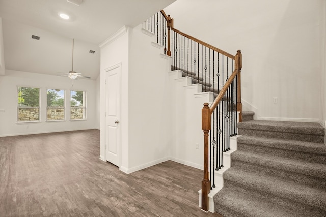 stairway featuring ceiling fan, a high ceiling, and hardwood / wood-style flooring