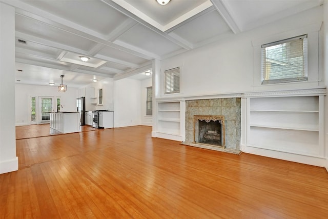 unfurnished living room featuring hardwood / wood-style flooring, a fireplace, built in shelves, beamed ceiling, and coffered ceiling