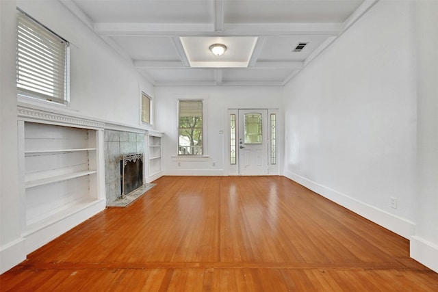 unfurnished living room featuring coffered ceiling, built in shelves, a high end fireplace, wood-type flooring, and beam ceiling