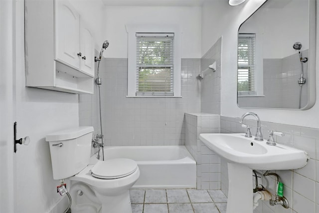 bathroom with tile walls, toilet, tile patterned floors, and tiled shower / bath